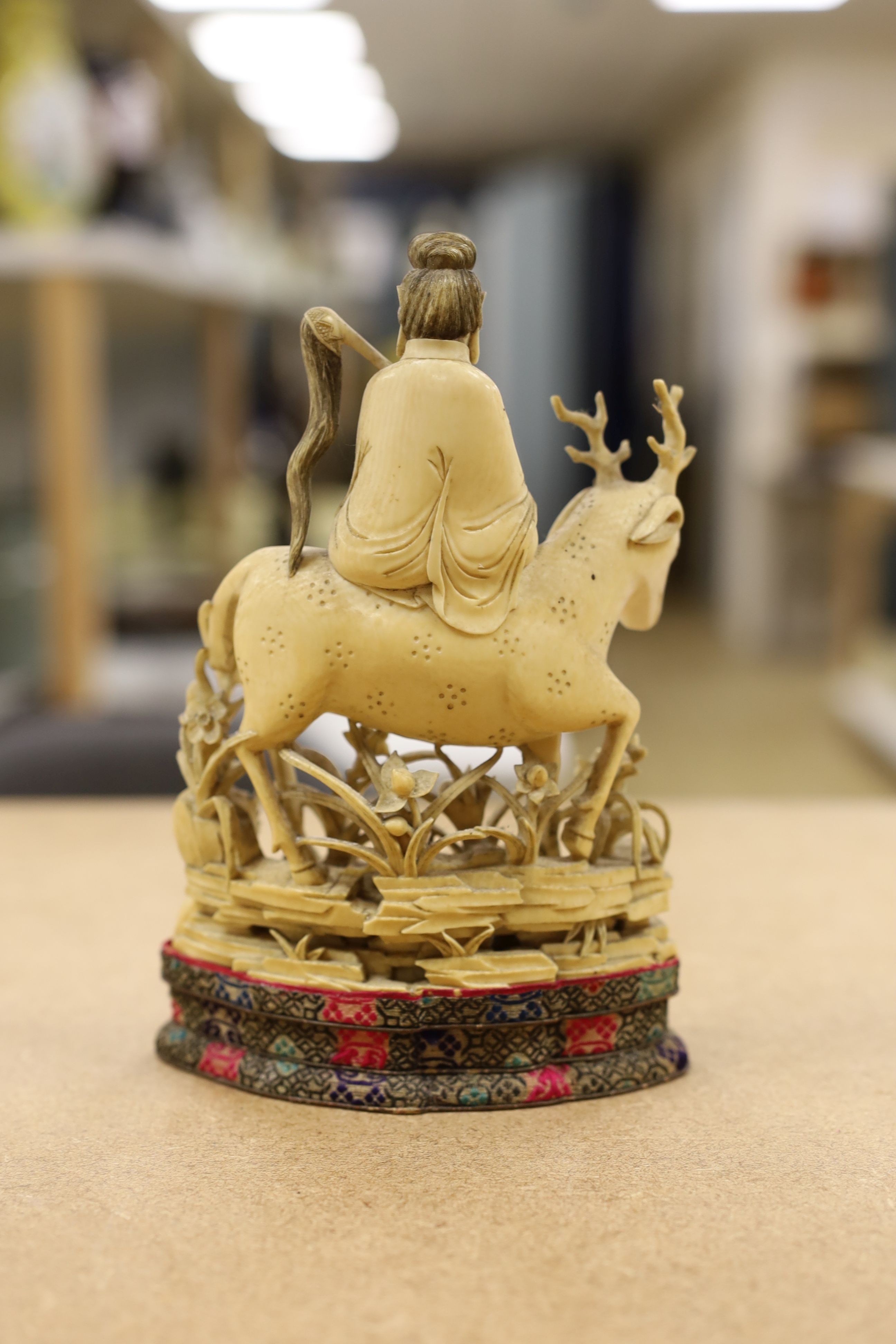 A Chinese carved ivory figure of a female immortal riding a deer, early 20th century, height 17cm excl. stand